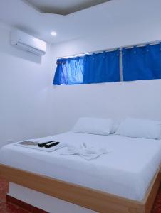 a bedroom with a white bed with a blue curtain at Hostal Martha in Neiva