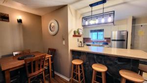 a kitchen with a bar and some wooden stools at Slope Lodge by AvantStay Prime Location PoolHot Tub Access Deck in Crescent Lake