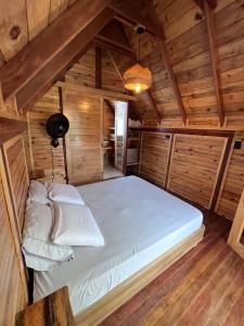 Cama grande en habitación con paredes de madera en Ecolodge Los Pinos, en Calima