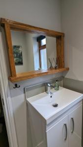 een badkamer met een witte wastafel en een spiegel bij Eakie House Apartments - Kinlochleven in Kinlochleven