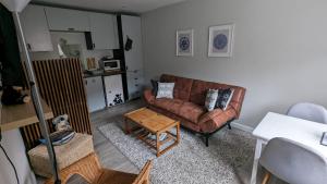 a living room with a brown couch and a table at Eakie House Apartments - Kinlochleven in Kinlochleven