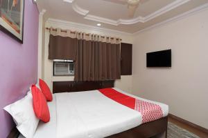 a bedroom with a bed with red pillows and a tv at OYO Hotel Bliss Executive Near Sant Tukaram Nagar Metro Station in Chinchwad