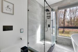 y baño con ducha de cristal y ventana. en The Barn House by AvantStay Modern Outdoor Living Area Hot Tub, en Albrightsville