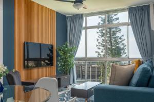 Una sala de estar con un sofá azul y un televisor. en Trendy @ La Ballito 503, en Ballito