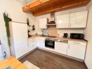 a kitchen with white cabinets and a wooden floor at Galeriewohnung Vierseithof in Eging