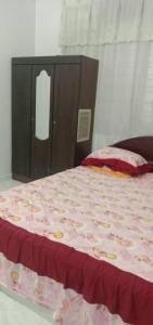 a bed with a pink bedspread and a wooden cabinet at Sobey Laris Homestay PASIR MAS LATI in Pasir Mas