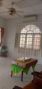 een woonkamer met een tafel en een raam bij Sobey Laris Homestay PASIR MAS LATI in Pasir Mas