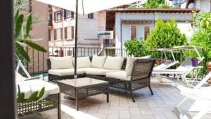 une terrasse avec un canapé, des chaises et un parasol dans l'établissement Wohnung in Toscolano Maderno mit Garten, Grill und Terrasse, à Toscolano Maderno