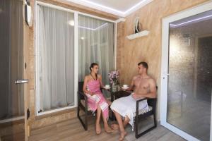 a man and woman sitting at a table in a room at Feniks Apartments in Nesebar