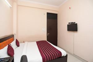 ein Schlafzimmer mit einem Bett und einem TV an der Wand in der Unterkunft OYO Rn 32 in Indirapuram