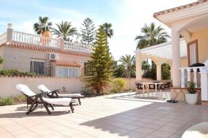 eine Terrasse mit Stühlen und Tischen sowie ein Haus in der Unterkunft Ferienhaus in Cartagena mit Privatem Pool - b58802 in Los Urrutias