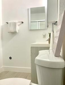 Baño blanco con aseo y lavamanos en Unique North Miami Bedrooms, en Miami
