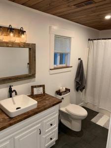 a bathroom with a sink and a toilet and a mirror at Journeys End Chalet - Minutes to Jay Peak! in Jay