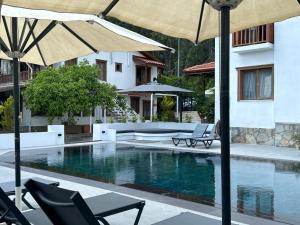 a pool with chairs and umbrellas next to a building at Tomsan Villas Akyaka in Akyaka