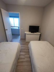 1 dormitorio con 2 camas y escritorio con ordenador portátil en Casa nieves, en San Pedro