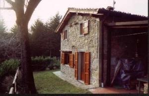 a stone house with a garage and a tree at Appartement in Bibbiena mit Grill, gemeinsamem Pool und Garten in Bibbiena