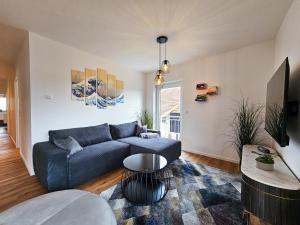 sala de estar con sofá azul y mesa en BETTER modern apartment II Tischkicker I Balkon I Parkplatz en Altusried