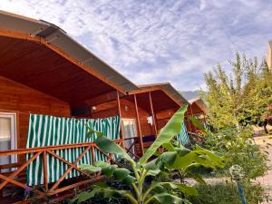 ein Holzhaus mit einer Veranda mit einem Zaun in der Unterkunft Adrasan Parlak Apart in Adrasan