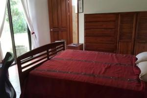 een slaapkamer met een houten bed en een rode deken bij Casona los Bambú in San José