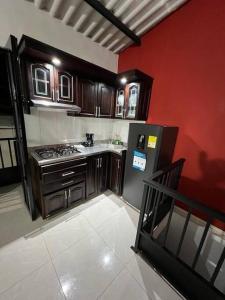 een keuken met een koelkast en een rode muur bij Acogedor apartamento en el centro histórico de Guaduas in Guaduas