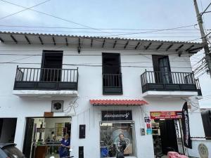 een wit gebouw met zwarte balkons en een winkel bij Acogedor apartamento en el centro histórico de Guaduas in Guaduas