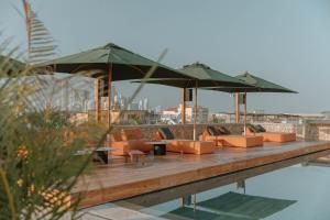 um deque com cadeiras e guarda-sóis ao lado de uma piscina em Osh Hotel Getsemani em Cartagena de Indias