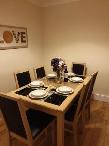 a dining room table with chairs and plates and flowers at Blodfa in Holyhead