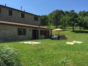 uma pessoa sentada numa mesa debaixo de um guarda-chuva num quintal em Ferienwohnung für 3 Personen 2 Kinder ca 65 qm in Colombara, Marken Provinz Pesaro-Urbino em Apecchio