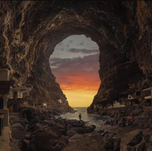 uma pessoa de pé na água em frente a uma caverna de rocha em Estudio los cipreses em Breña Alta