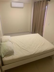 un letto non rifatto in una stanza con finestra di Otimo apartamento de 02 quartos a Cabo Frio
