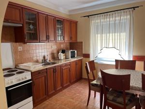 a kitchen with wooden cabinets and a table with a sink at Apartment Villa Attila in H&eacute;v&iacute;z