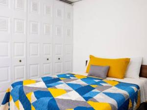 a bedroom with a bed with a blue and yellow quilt at Cozy Two Bedroom Apartment Near The U.S. Embassy in Antiguo Cuscatlán