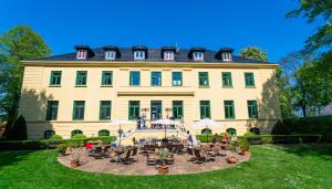 un grand bâtiment avec des tables et des chaises devant lui dans l'établissement Schloss Harkensee, à Dassow