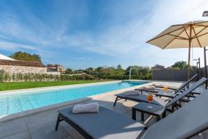 uma piscina com duas mesas e um guarda-chuva em Villa Daniela für 6 Personen in Porec, Salzwasserpool, Garten mit Grill em Veleniki