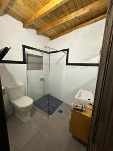 a bathroom with a toilet and a glass shower at Casa Rama San Pedro in San Pedro