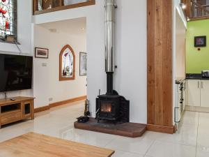 a fireplace in a living room with a tv at Old St Lukes Church in Soulby