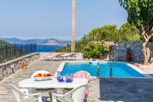 a table and chairs next to a swimming pool at Avgeri Villa in Skopelos Town