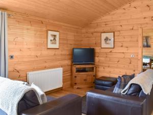 a living room with a tv and leather furniture at Bank End Lodge in Carlton