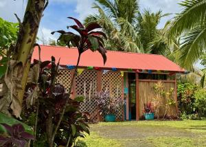 a house with a red roof in a garden at Tropical Zen Bungalow in Pahoa