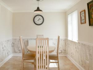 a dining room with a table and chairs and a clock on the wall at Little Bere in Lifton