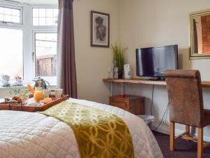 a bedroom with a bed and a desk with a television at Little Lodge in Walcote