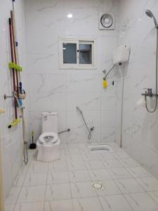 y baño blanco con aseo y ducha. en فلل فندقية بمدينة تنومة en Ithnayn
