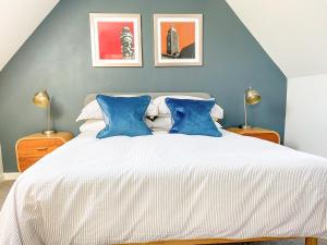 a bedroom with a large white bed with blue walls at Honey Bee Cottage in Calbourne