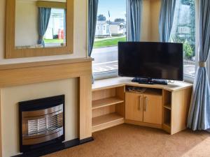 a living room with a fireplace and a flat screen tv at Swift Johnson in Dovercourt