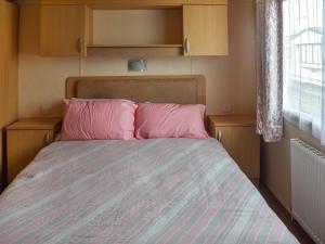 a bedroom with a bed with pink pillows and a window at Swift Johnson in Dovercourt