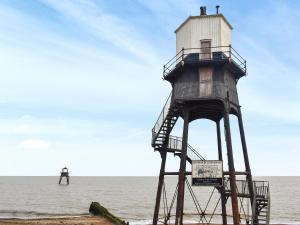 a lighthouse on the beach with a man in the ocean at Swift Johnson in Dovercourt
