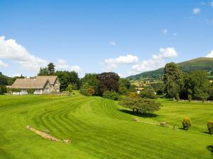 a field of green grass with a house in the background at Glanusk Lodge - Uk46654 in Crickhowell