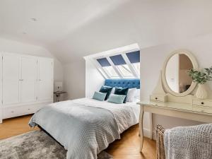 a white bedroom with a bed and a mirror at Stargazing in Filby