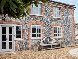 a brick house with a bench in front of it at Eden Hall Cottage in Bacton