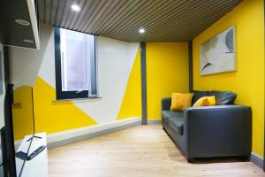 ein Wohnzimmer mit gelben Wänden und einem Sofa in der Unterkunft E104 Urban loft gem in Coventry